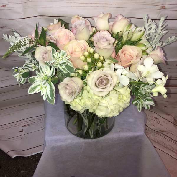 Pastel rose bouquet in a glass vase with white filler flowers
