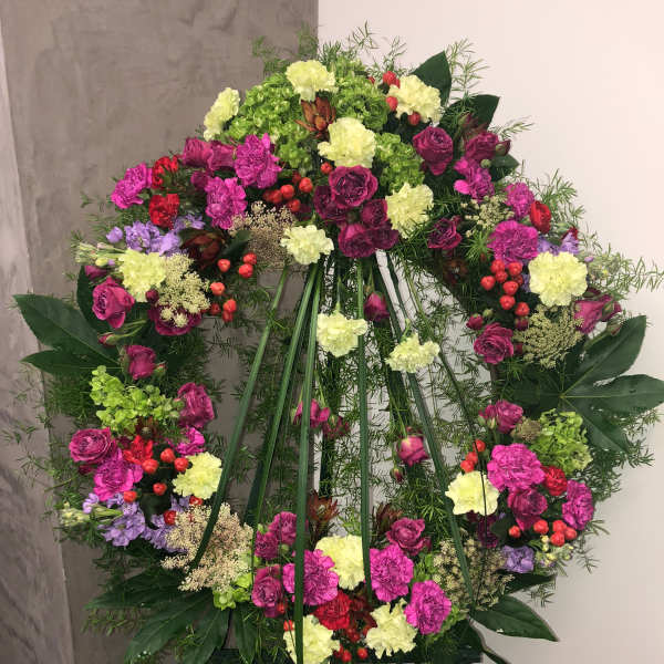 Large floral wreath on an easel with pink, yellow, and purple blooms