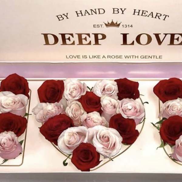 Boxed arrangement of red and pale pink roses in heart shapes