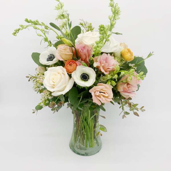 Pastel bouquet of mixed flowers arranged in a clear glass vase.