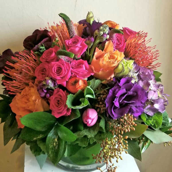 Colorful bouquet of roses, hydrangea, and tropical blooms in a glass vase