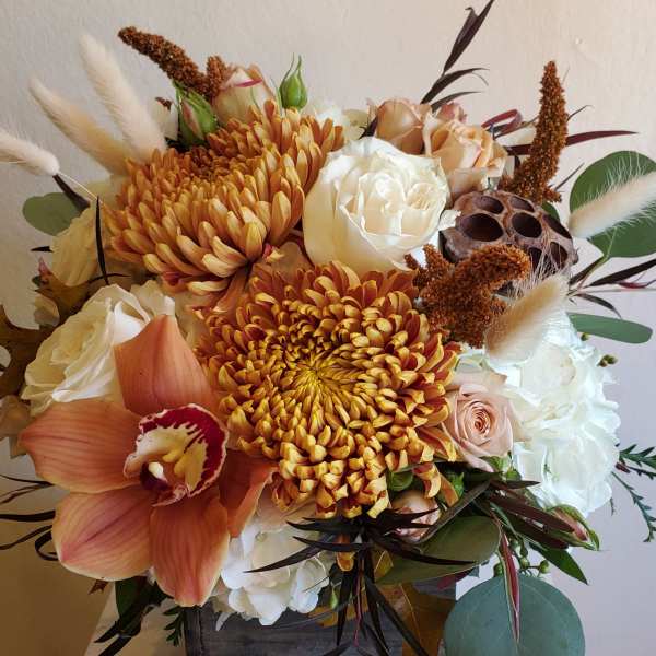 Autumn bouquet with orange chrysanthemums, white roses, and an orchid in a wooden box