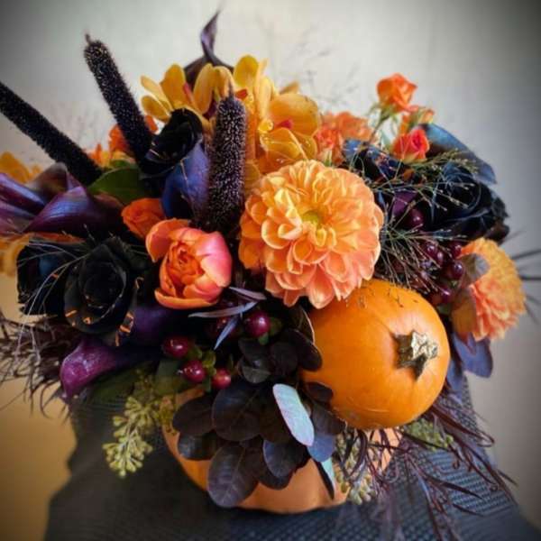 Orange and black floral arrangement with pumpkins and autumn blooms
