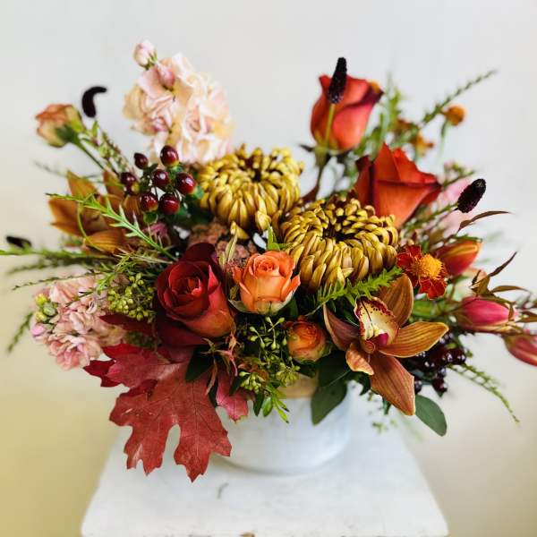 Autumn bouquet of roses, orchids, and mums in a white vase