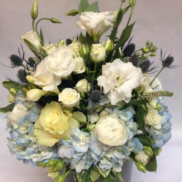 White and pale blue floral arrangement in a gray vase