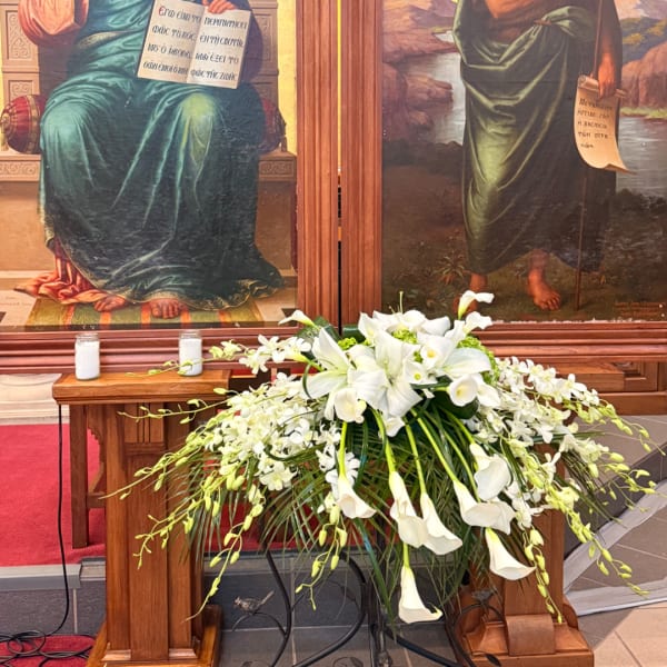 White floral arrangement with lilies and calla lilies on a wooden altar