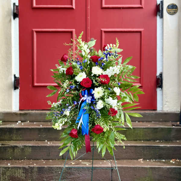 Standing floral spray with red and white flowers and blue ribbon