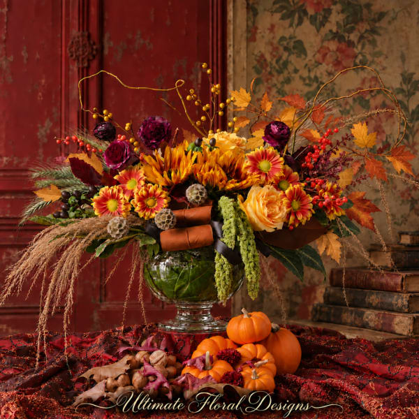 Autumn floral arrangement in a glass vase with pumpkins and berries