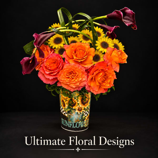 Bouquet of orange roses, sunflowers, and dark calla lilies in a printed tin container