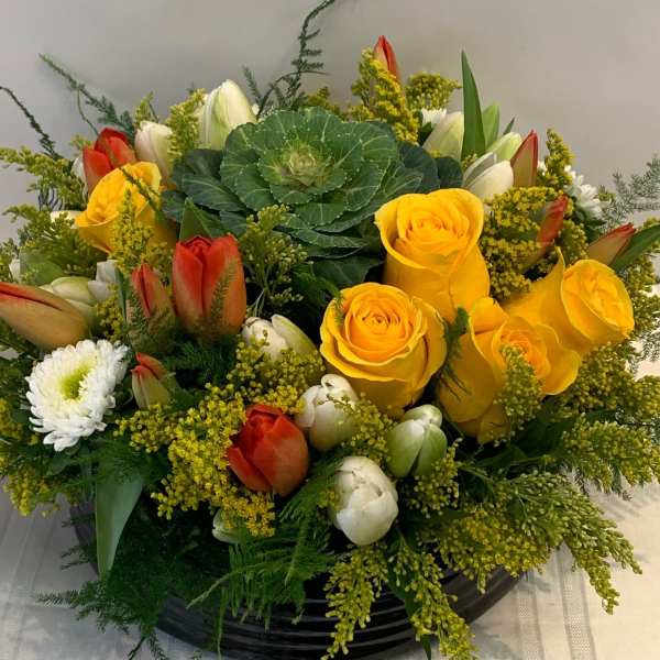 Yellow roses and red tulips arranged in a black bowl vase