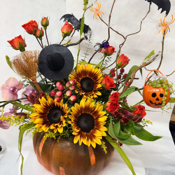 Halloween floral arrangement in a pumpkin container with sunflowers and roses