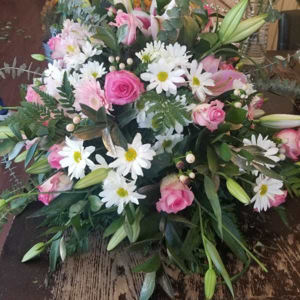 Pink roses and white daisies in a lush bouquet with lily buds