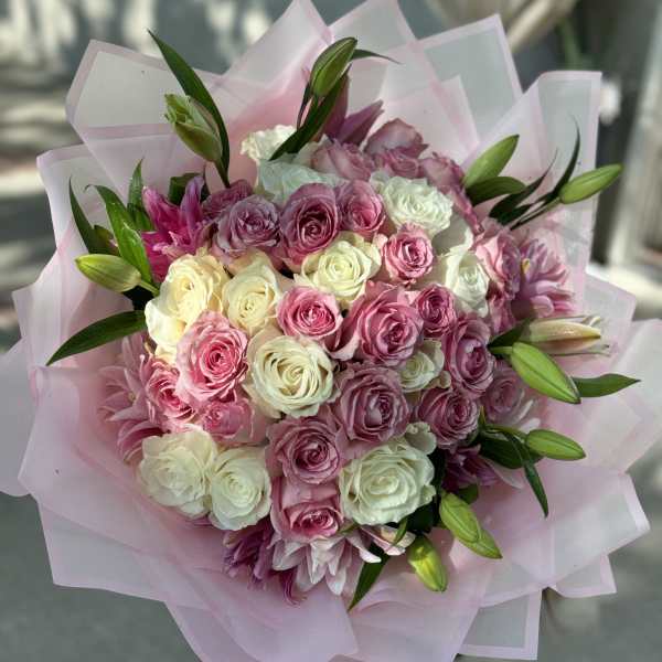 Bouquet of pink and white roses with lily buds wrapped in pale pink paper