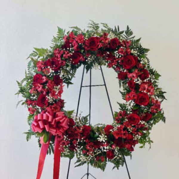 Red rose wreath on a black stand with a pink bow