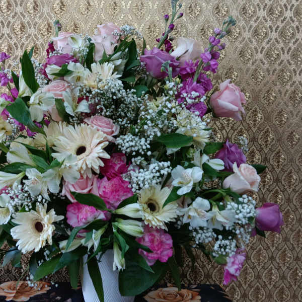 Large mixed bouquet of pink, white, and purple flowers in a white vase