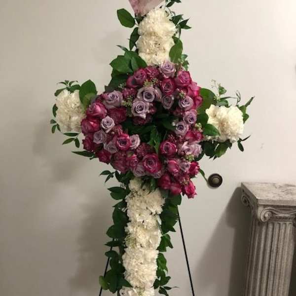 Standing floral cross with pink roses and white flowers on an easel