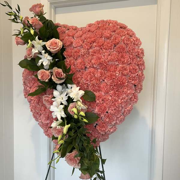 Pink floral heart on an easel with roses and white orchids