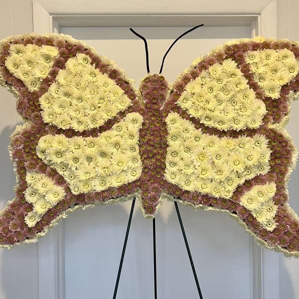 Butterfly-shaped floral standing spray with pale yellow and pink chrysanthemums
