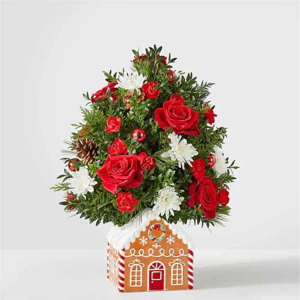 Christmas tree arrangement with red roses and white daisies in a gingerbread house container
