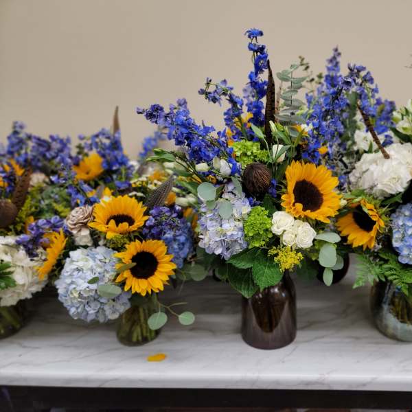 Blue and yellow floral arrangements in glass vases