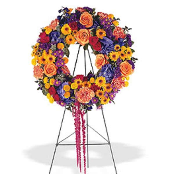 Vibrant multicolor wreath of roses, carnations, and daisies displayed on a standing easel
