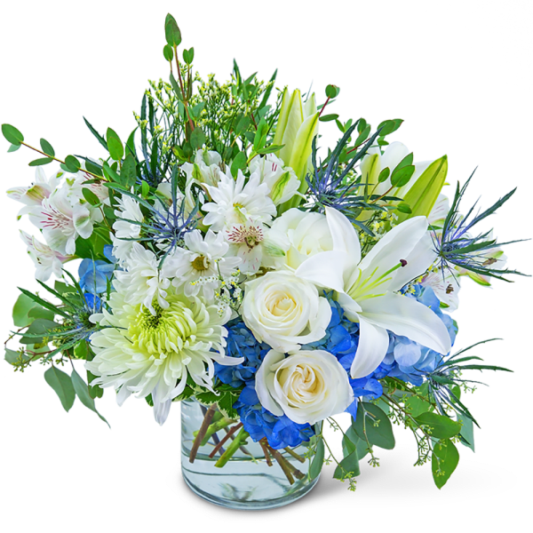 White lilies and roses with blue hydrangeas in a glass vase