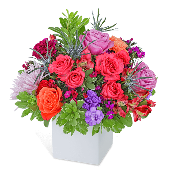 Mixed bouquet of roses and other flowers in a white square vase