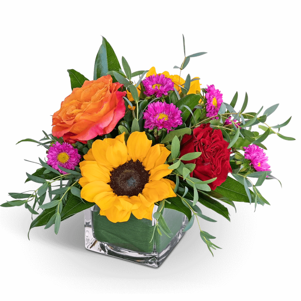 Mixed bouquet with sunflowers, roses, and purple daisies in a glass vase