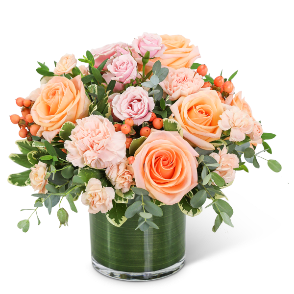 Peach and pink roses with carnations in a glass vase