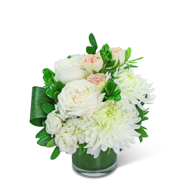 White roses and chrysanthemums in a glass vase with green leaves