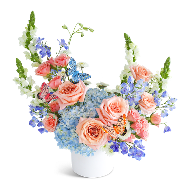 Peach roses and blue hydrangeas in a white vase with butterfly picks