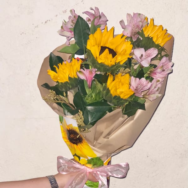 Bouquet of yellow sunflowers and pink alstroemeria wrapped in paper