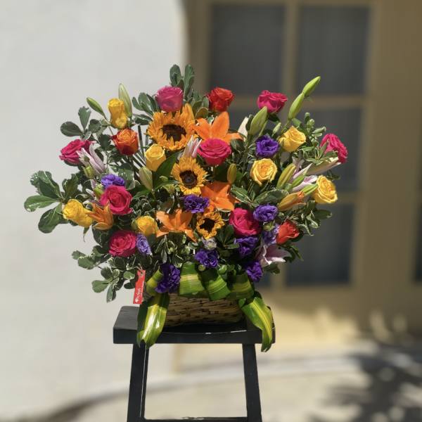 Colorful mixed bouquet with roses, sunflowers, and lilies in a basket