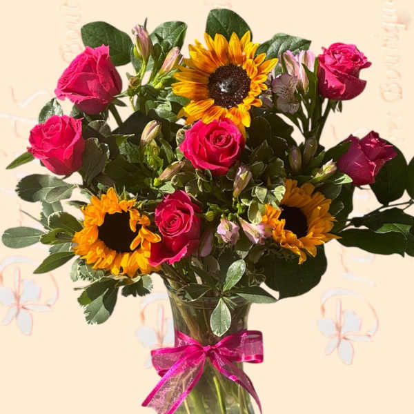 Bouquet of pink roses and sunflowers in a glass vase with a pink ribbon