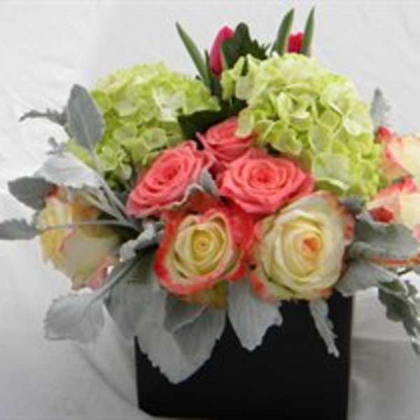 Bouquet of pink and cream roses with green hydrangeas in a black box