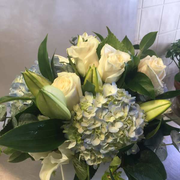 White roses and pale blue hydrangeas in a square vase