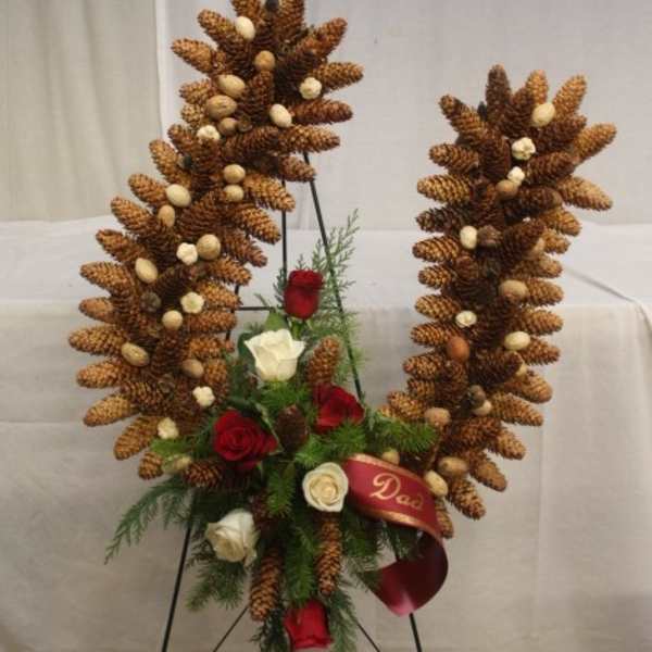 Pinecone wreath with red and white roses on a stand