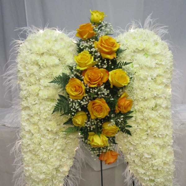White floral standing spray with yellow roses on a metal easel