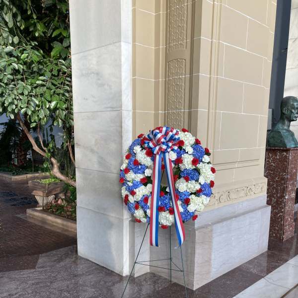 Large red, white, and blue floral wreath on a stand with ribbon