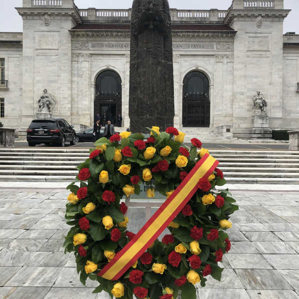 Circular wreath of red and yellow roses with a ribbon on a stand