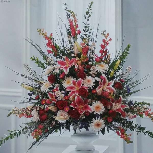 Large mixed floral arrangement in a white pedestal vase