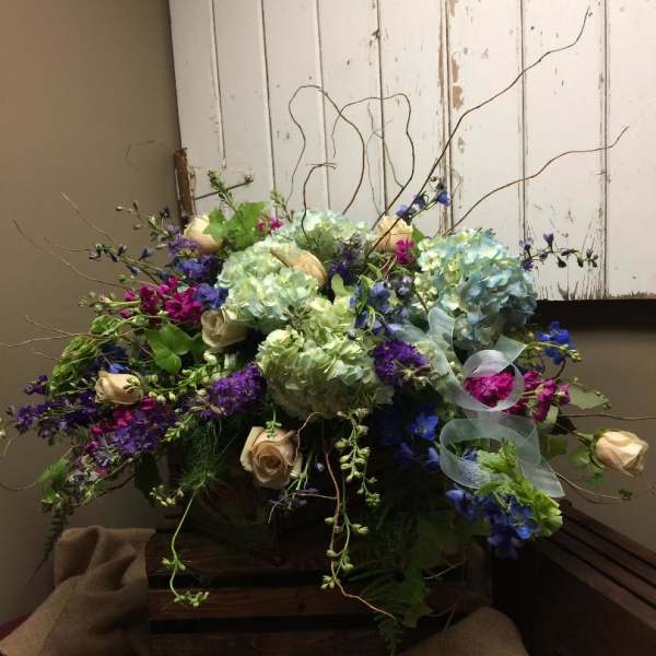 Mixed bouquet with hydrangeas, roses, and purple flowers in a wooden box