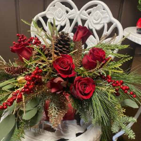 Red roses arranged with pinecones and berries in a white chair