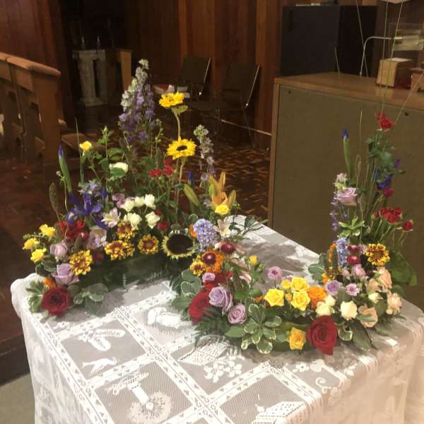 Colorful floral arrangements on a lace-covered table in a church interior
