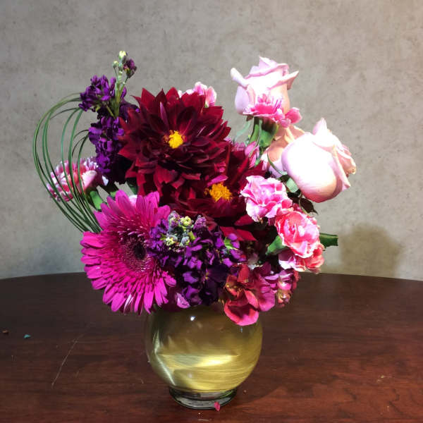 Bouquet of pink, purple, and burgundy flowers in a gold vase