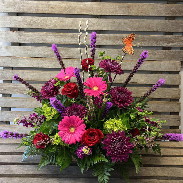 Bright mixed flower arrangement with roses, gerbera daisies, and purple blooms