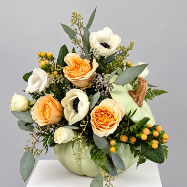Pumpkin-shaped vase with peach and white flowers and greenery