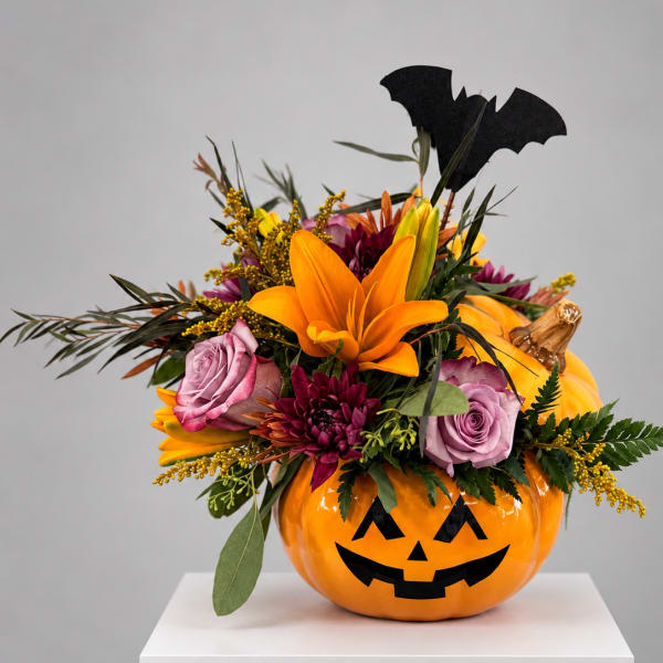 Halloween floral arrangement in a jack-o'-lantern container with roses and lilies