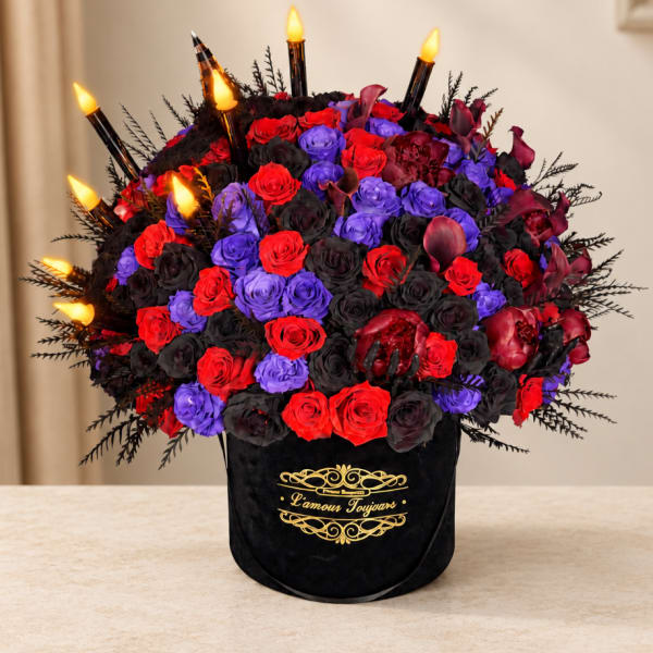 Red, purple, and black roses arranged in a black box with candle picks