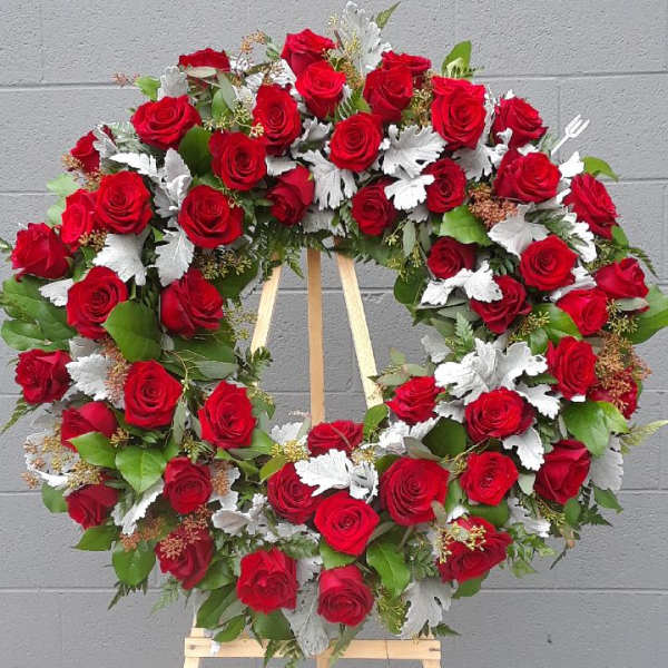 Red rose wreath on a wooden easel with silver foliage accents